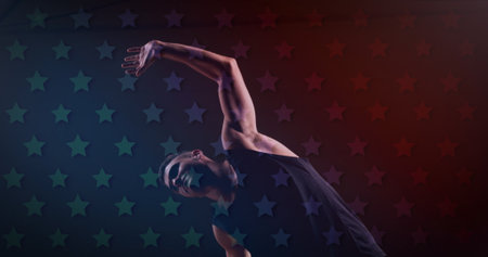 Caucasian male fan in black tank top stretching against starry background. Sporting short brown hair, displaying fit physique, enjoying night skyの写真素材