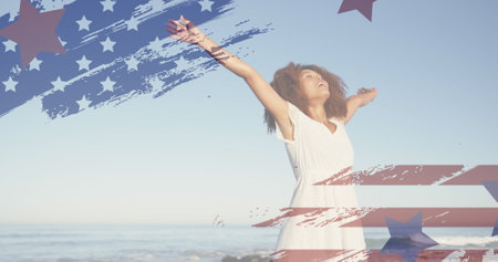 Image of american flag over african american woman raising hands at beach. patriotism and celebration concept digitally generated image.の写真素材