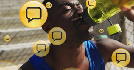 Image of message boxes icons, tired african american athlete drinking water after training. Digital composite, multiple exposure, speech bubble, drink, sports and competition concept.の写真素材