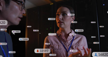 Image of social media icons over diverse male and female it engineers by computer server. digital interface, cloud computing concept and technology concept digitally generated image.の写真素材