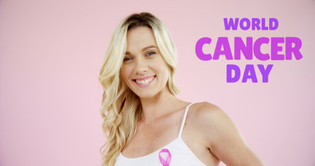 Image of world cancer day over happy caucasian woman on pink background. cancer awareness and world cancer day concept digitally generated image.の写真素材