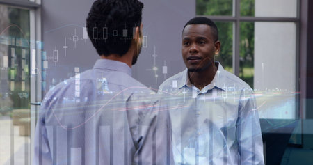 Image of financial graphs over diverse businessmen talking in office. global business, finance, economy and technology concept digitally generated image.の写真素材