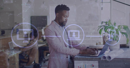 Image of media icons over african american businessman using laptop in office. Global business and digital interface concept digitally generated image.の写真素材