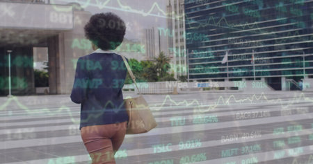 Image of trading board over of african american woman talking on cellphone and crossing road. Digital composite, multiple exposure, stock market, business, abstract and technology concept.の写真素材