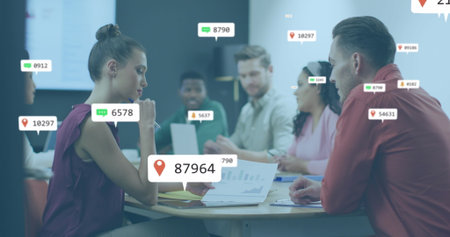 Image of social media icons over diverse man and woman discussing over a document at office. Social...