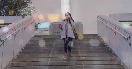 Image of lens flares over asian woman taking on smartphone while moving down on steps in city....