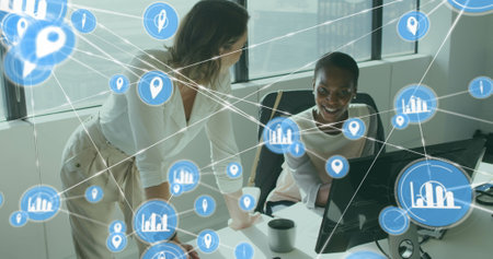 Image of connected icons over diverse female coworkers discussing reports on computer. Digital composite, multiple exposure, shopping, planning, teamwork, communication and technology concept.の写真素材