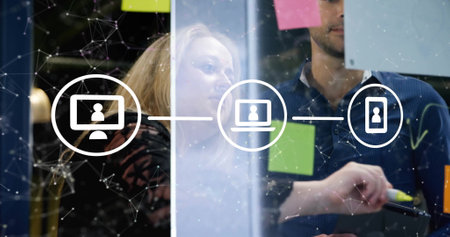 Image of flowchart of icons and connected dots, diverse coworkers brainstorming on glass wall....