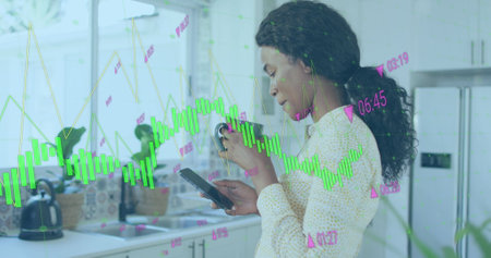 Image of graphs with changing numbers, biracial woman scrolling on cellphone while drinking tea....