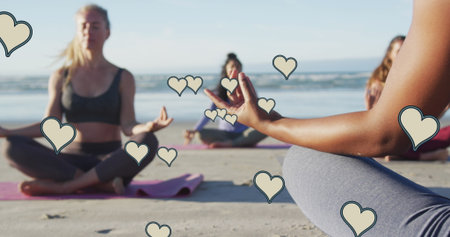 Image of yellow hearts over women practicing yoga on beach. health, hobbies and wellbeing concept digitally generated image.の写真素材