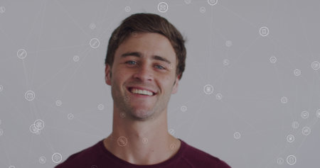 Image of network of connections with icons over caucasian man smiling at camera. global connections,...