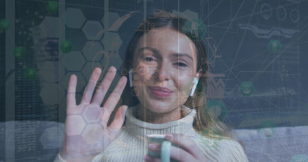 Image of network of connections and data over caucasian woman smiling and waving at camera. global connections, technology and digital interface concept digitally generated image.の写真素材