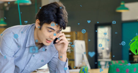 Image of icons connected with lines over caucasian man talking on smartphone in office. Digital...