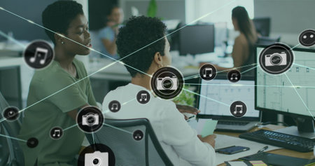 Image of connected icons over diverse female coworkers discussing reports on computer. Digital...