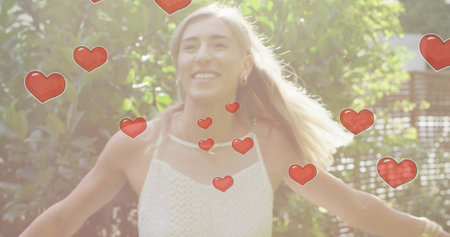 Image of hearts floating over caucasian woman wearing wedding dress dancing. Pride, lifestyle and celebration concept digitally generated image.の写真素材