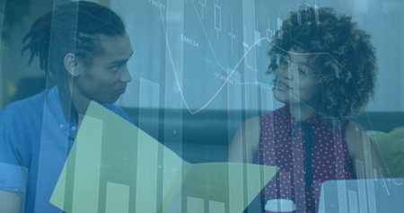 Financial data charts image over two people discussing documents in officeの写真素材