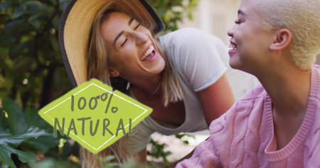 Image of 100 percent natural text over diverse female couple working in gardenの写真素材