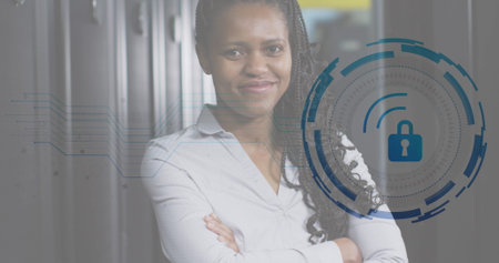 Image of padlock icon and african american female engineer standing in data centre. Digital composite, network security, protection, networking, technology, network server, portrait, happy.の写真素材