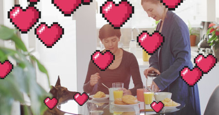 Image of heart emojis over happy caucasian female couple with dog. Love, romance and celebration concept digitally generated image.の写真素材