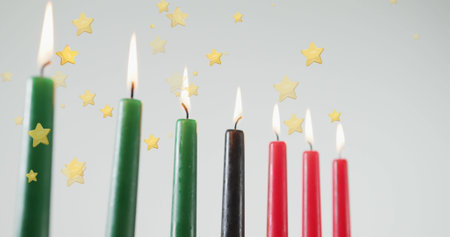 Image of golden stars falling over kwanzaa candles on grey background. Kwanzaa festivity, celebration and tradition concept digitally generated image.の写真素材