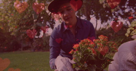 Image of heart emojis over caucasian woman gardening. Love, romance and celebration concept digitally generated image.の写真素材