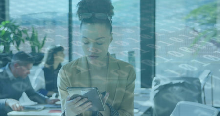 Image of data processing over african american businesswoman using tablet at office. Global business, finances and digital interface concept digitally generated image.の写真素材