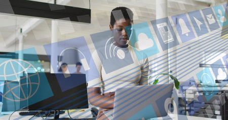 Image of business icons and data over diverse african american businesswoman using laptop. Global business and digital interface concept digitally generated image.の写真素材