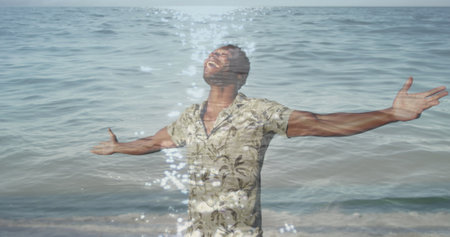 Image of sea over african american man with arms outstretched. never give up day and celebration concept digitally generated image.の写真素材