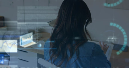 Image of financial data processing over woman using tablet. Global business, finances, computing and data processing concept digitally generated image.の写真素材