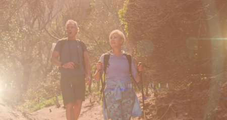 Caucasian senior couple in hiking in countryside, over lens flare and bokeh city lights. active,...