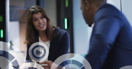 Image of statistic icons over diverse male and female business colleagues talking in office. global...