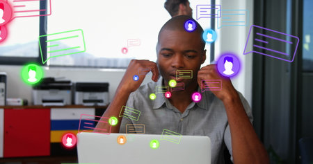 Image of profile icon and message boxes over tired african american man working on laptop. Digital...