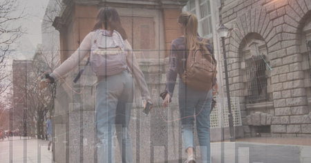 Image of financial data and graphs over back view of caucasian female friends. finance, economy,...