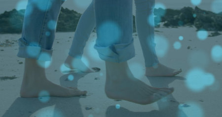 Image of light spots over caucasian couple at beach. Holidays and digital interface concept digitally generated image.の写真素材