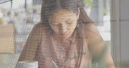 Image of data processing against asian woman writing in her notepad at a cafe. Computer interface...