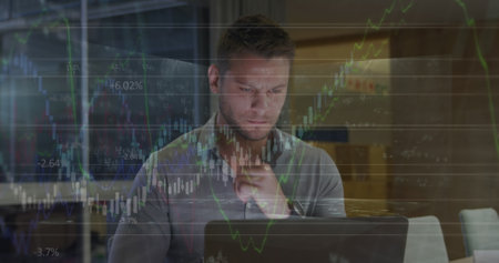 Image of financial data over caucasian businessman working on laptop in office. economy, finance,...
