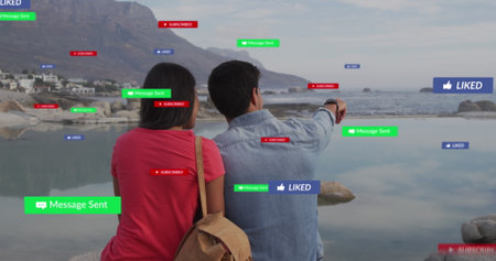 Image of social media text and icons over biracial couple on beach. Global social media, digital...