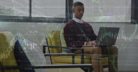 Image of financial data over african american businessman working on laptop in office. economy, finance, business and technology concept digitally generated image.の写真素材