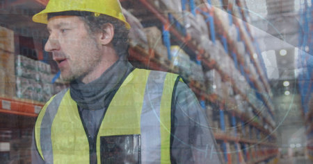 Composite image of surveillance camera over caucasian male supervisor walking at warehouse....