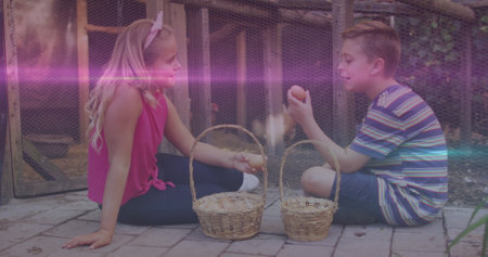 Pink and blue light trails against caucasian brother and sister holding eggs in the farm. national siblings day awareness conceptの写真素材