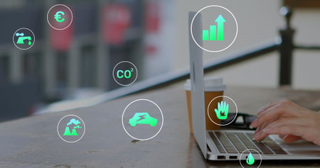 Image of multiple icons over cropped hands of caucasian woman working on laptop in cafes. Digital composite, multiple exposure, hazardous, recycling, beverage and technology concept.の写真素材