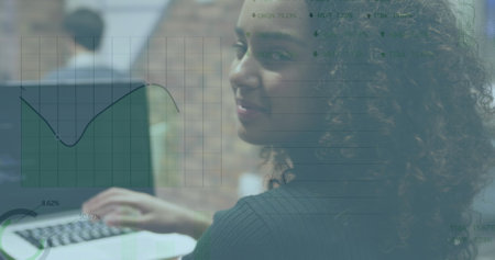 A biracial businesswoman working in a modern office and using a laptop computer. She turns to the...