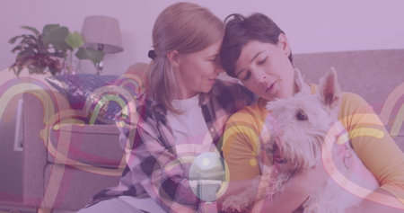 Image of hearts and ballons over caucasian female couple sitting on sofa with their pet dog. Valentines, love and celebration concept digitally generated image.の写真素材
