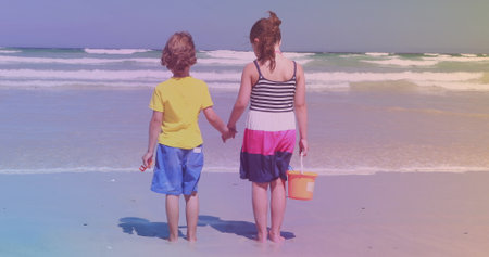 Rear view of caucasian brother and sister standing at the beach. national siblings day awareness conceptの写真素材
