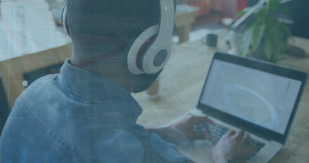 Image of statistical data processing over rear view of african american man using laptop. Business data technology conceptの写真素材