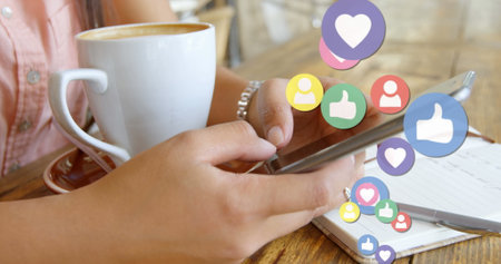 Close up of a woman texting with a coffee on the table and social media icons floating on the right...