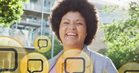 Image of message icons over smiling african american woman in city. Global connections, networks,...