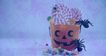 Spiders and candies in halloween scary pumpkin bucket against textured white background. halloween...