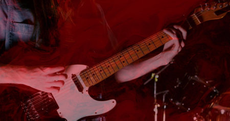 Image of glowing red lights over mid section of caucasian man playing guitar. Music, performance and...