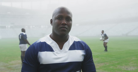 African American colleagues in rugby attire on misty field. They have short hair, focused expressions, and are fitの写真素材